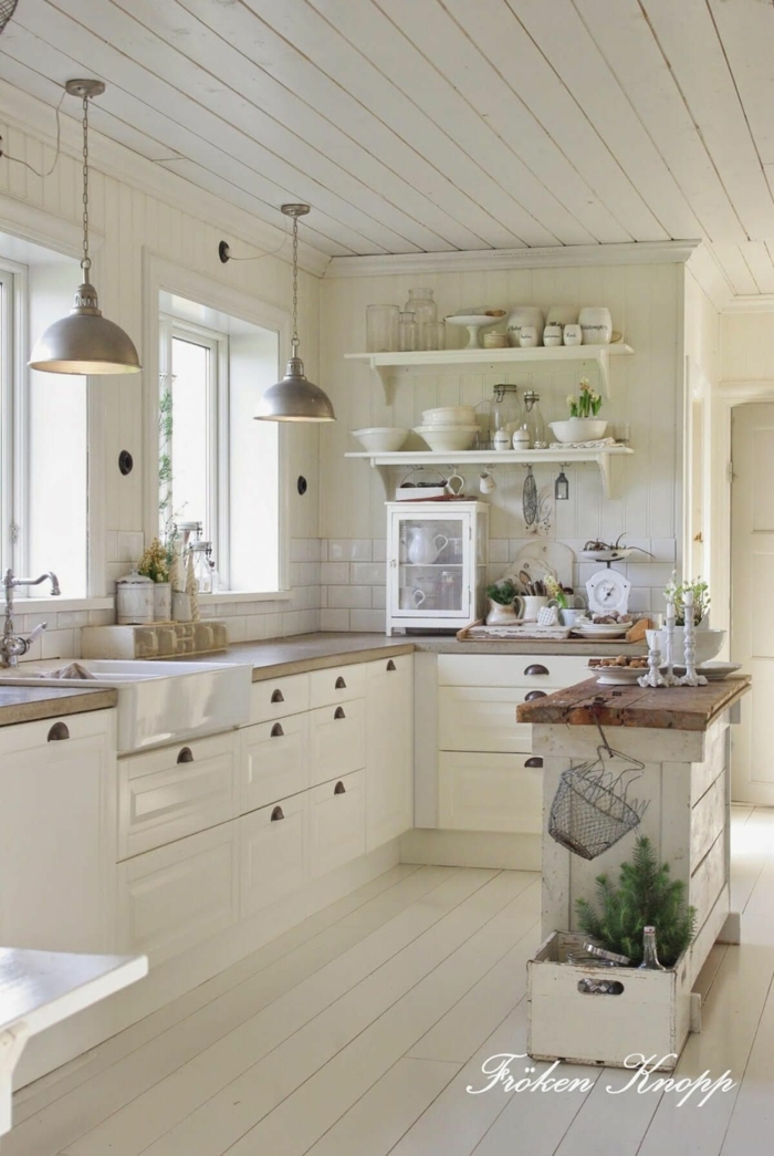 salon cocina en blanco con armarios, techo y paredes en color crema con lamapras de metal colgantes
