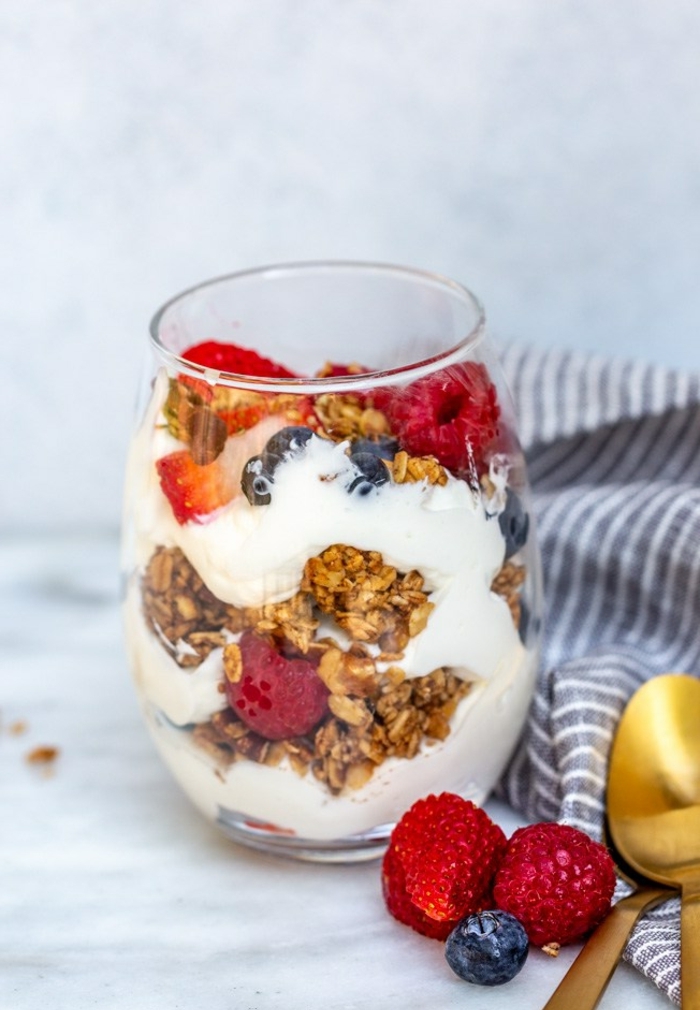 ideas de desayunos fitness super fáciles, yogur con cereales, frambuesas y arándanos frescos 