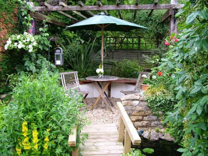 jardines modernos pequeñas decoradas de mucho estilo, suelo con grava, puente de madera y mucha vegetación 