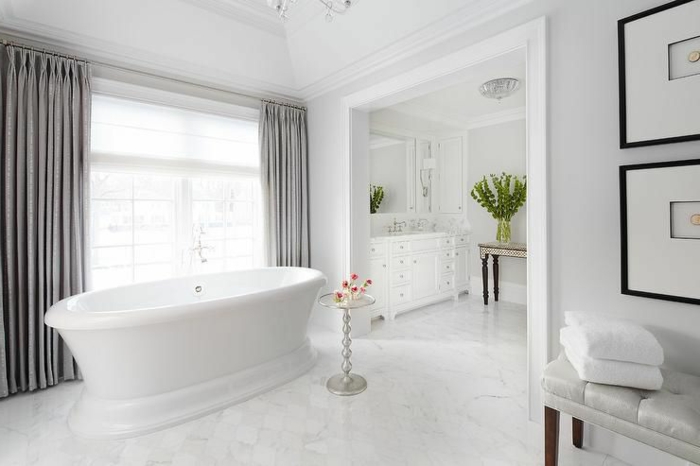cuartos de baño modernos decorados enteramente en blanco, cortinas en plateado, suelo de marfil y decoración cuadros en la pared 
