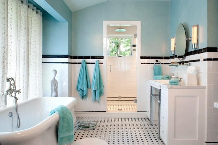 decoracion baños pequeños en blanco y azul, techo inclinado, suelo con azulejos en blanco y negro y bañera moderna