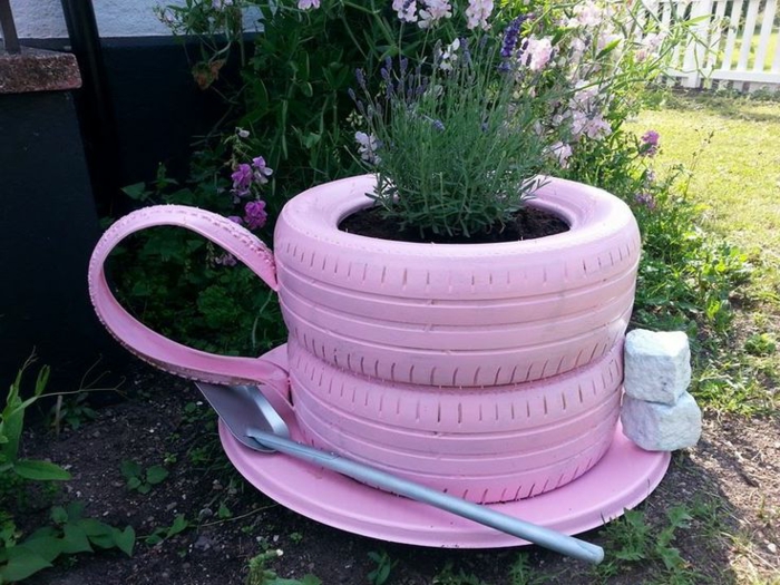 decoracion de jardines, taza rosa hecha de neumáticos y con flores plantadas dentro con pala como cucharra