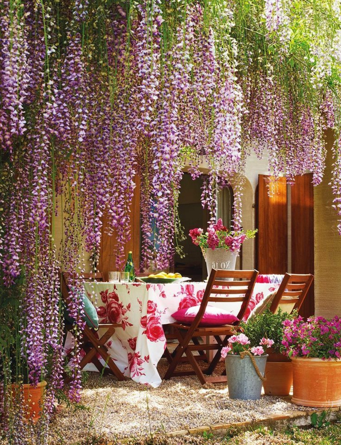 decoracion jardin, mesa con mantel blanco con flores grades rosas y cubo de flores vivas en la mesa