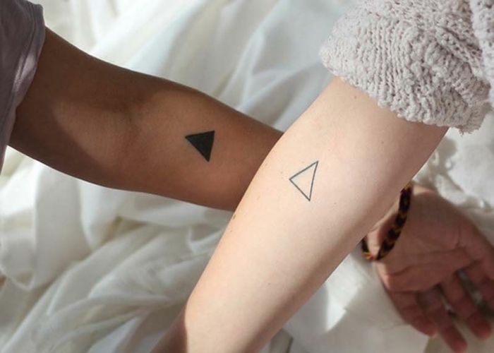 tatuajes simbolicos para amigas y hermanas, dos triangulos de diferente diseño tatuados en el antebrazo 