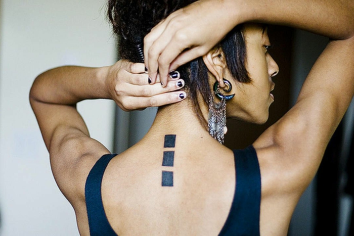tattoos pequeños en la espalda, diseños simbólicos con figuras geométricas, tres cuadros negros en la columna vertebral 