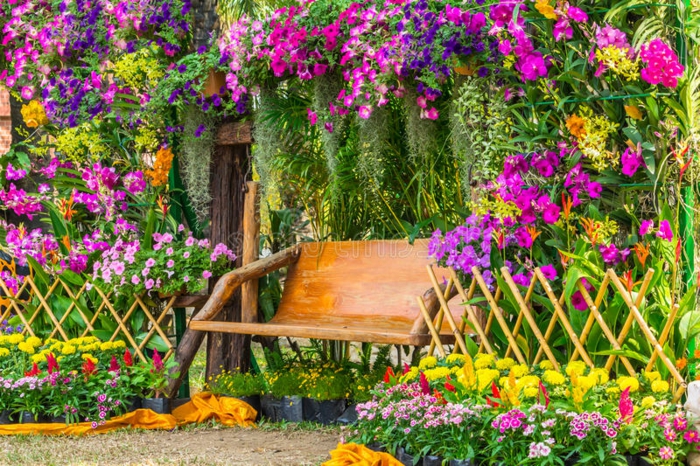 decoracion patios exteriores, banco de madera y decoración de muchas flores de diferentes colores