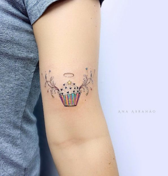 tatuajes en el brazo pequeños ideas simbólicas coloridas, muffin con alas angélicas en colores pastel 