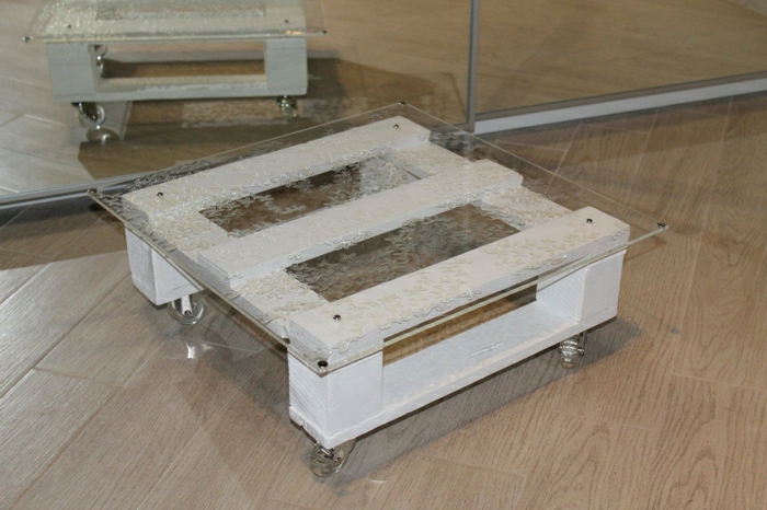 pequeña mesa cuadrada con vidrio encima sujeto con tapas metálicas y con ruedas transparentes, mesas con palets