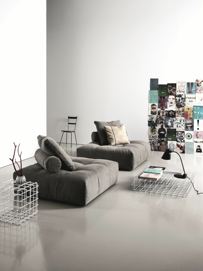 decoracion salon pequeño decorado con sofa de suelo en gris oscuro con cojines cuadrados y de tubo, con imagenes en la pared
