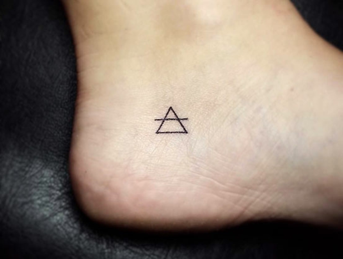 tatuajes simbolicos con triángulos, pequeño tiángulo en el pie con una línea, ideas tatuajes minimalistas 