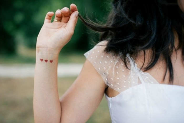 diseños de tatuajes para mujeres en la muñeca, tres corazones pequeños en rojo tatuados en la muñeca