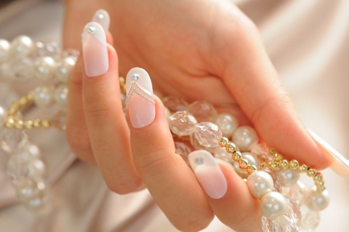 diseños de uñas de gel francesas para novias, uñas muy largas en rosado suave y blanco con cristales decorativos 