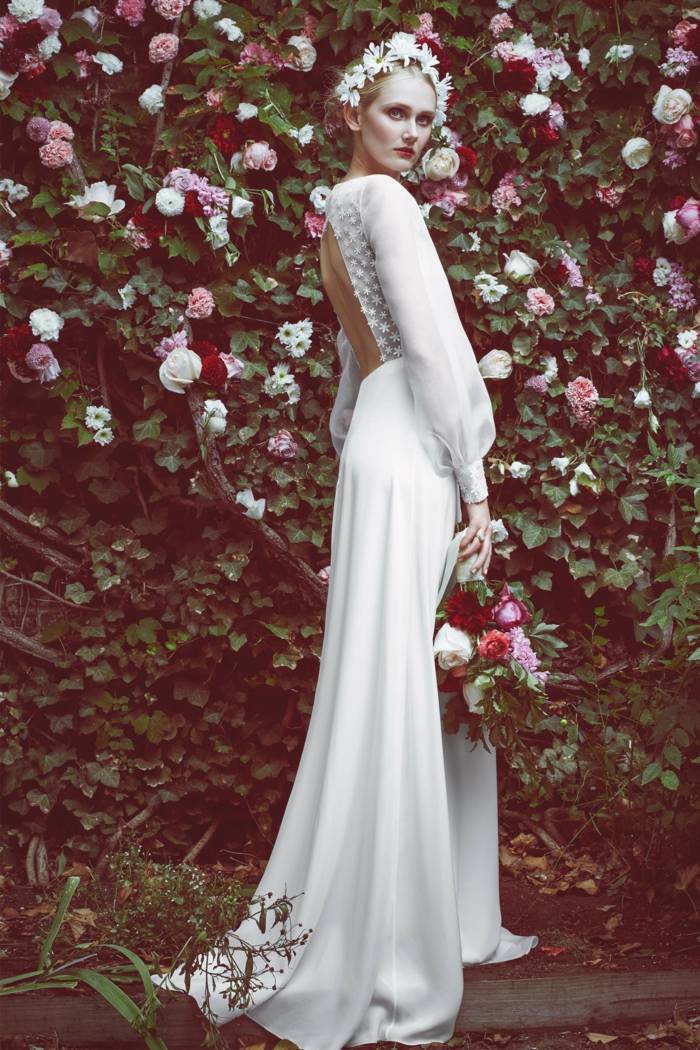 largo vestido en blanco con espalda descubierta, mangas transparentes de visillo, corona de flores blancas en el pelo 