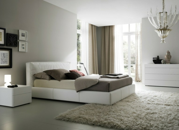 feng shui dormitorio con cama de cuero blanca con alfombra en color beige de pelos, araña de luces
