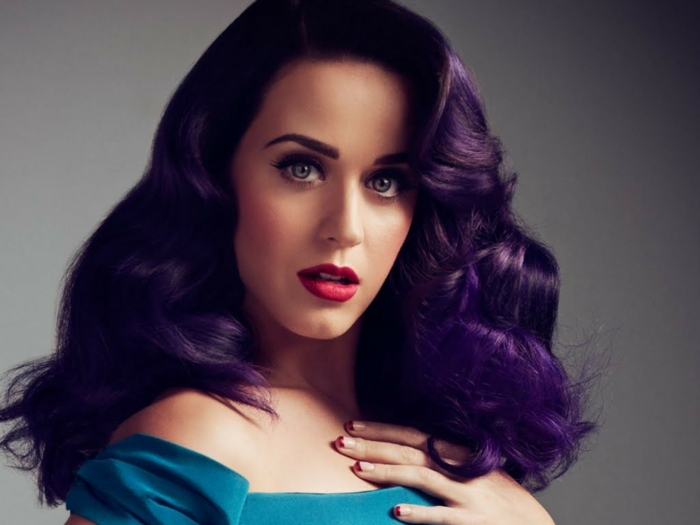 Katy Perry con color de pelo morado oscuro, vestida con vestido azul, mechas para pelo castaño