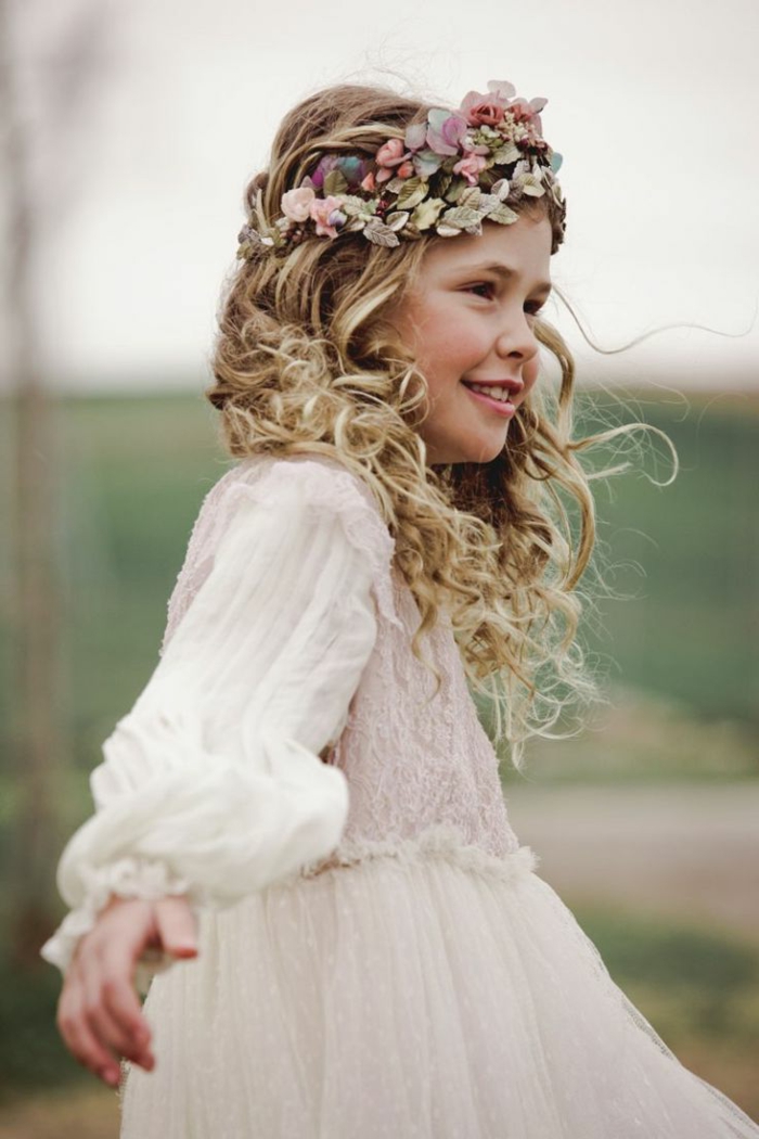 peinados con trenzas faciles con el pelo largo rubio y rizado con diadema de flores en la cabeza, vestido blanco