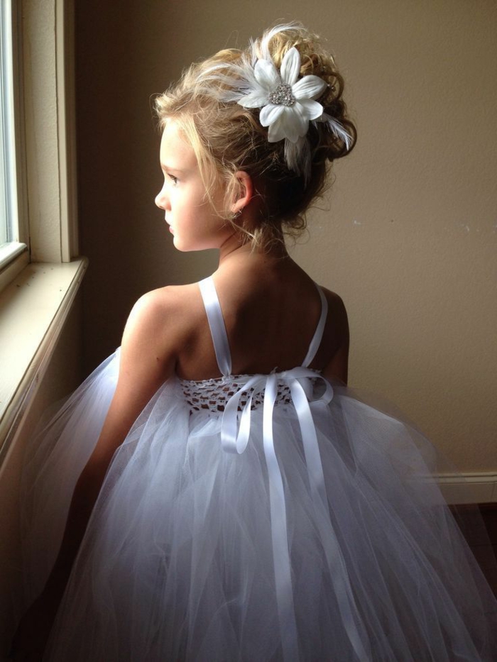 peinados faciles y rapidos, niña con el pelo en un moño alto decorado con una flor grande, vestido blanco