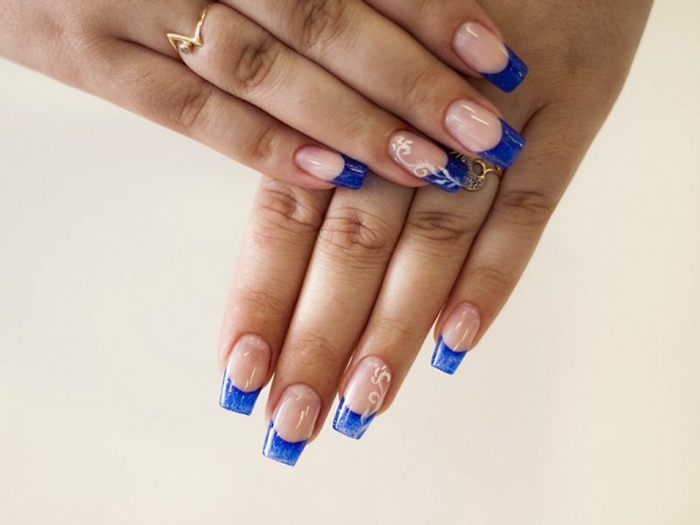 uñas largas francesas con puntas decoradas en azul oscuro, elementos florales en blanco 
