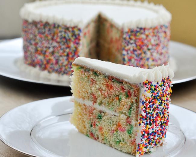 tarta de cumpleaños hecha de bizcocho con crema de leche, glaseado de vainilla y bolitas de azucar