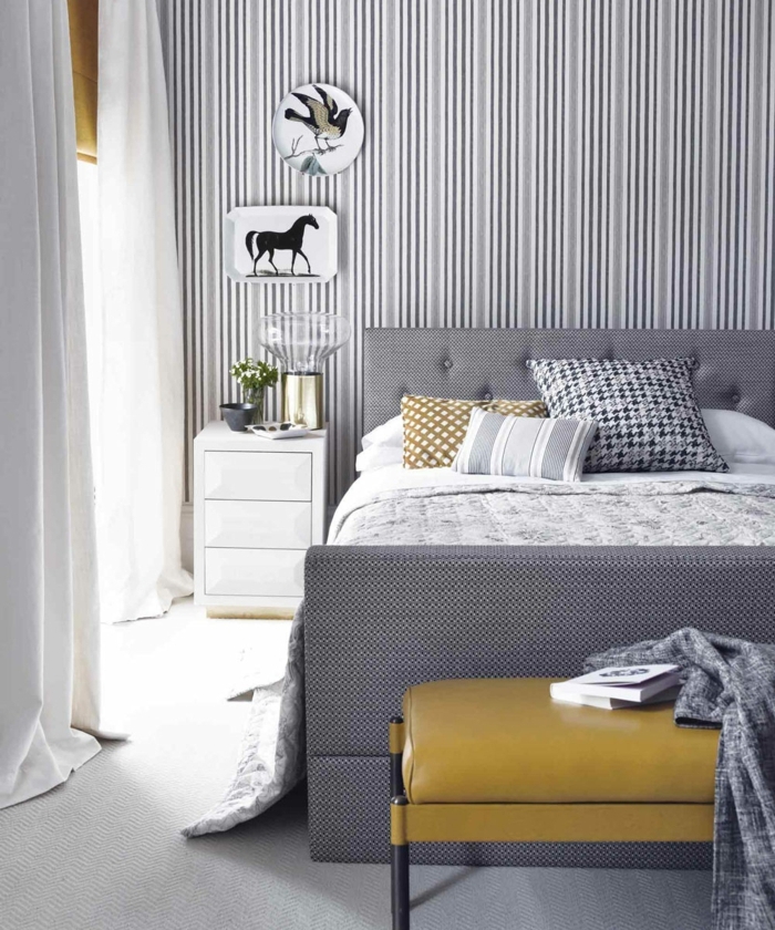 decoracion apartamentos pequeños, cama gris con cabecera alta con vinilo de rayas verticales