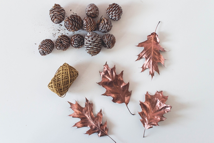 materiales necesarios para hacer una guirnalda para decorar la casa en otoño, piñas, hilo dorado, hojas secas pitnadas 