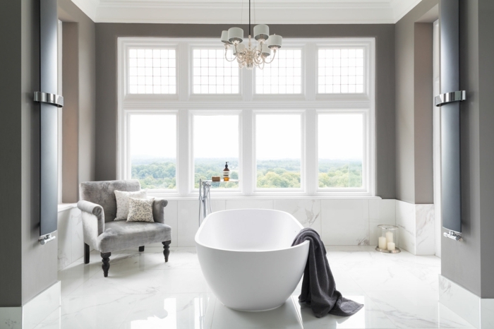azulejos imitacion madera, bañera blanca con toalla gris colgando en ella, ventana grande en toda la pared