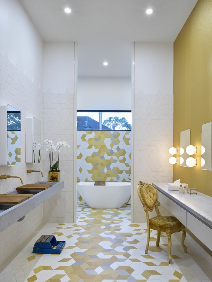 baldosas baño de colores amarillo mostaza, blanco y gris claro, silla de color amarillo, luces y espejos