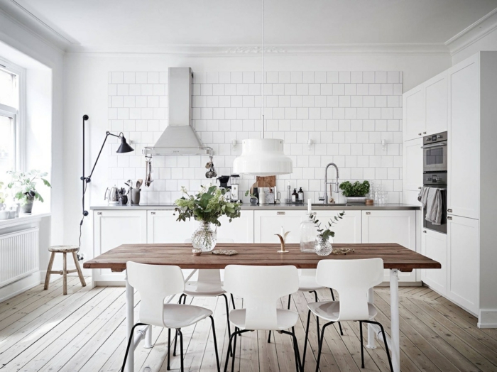 cocinas blancas con mucho encanto, mesa y suelo de madera, decoración en blanco, jarrones con plantas verdes 