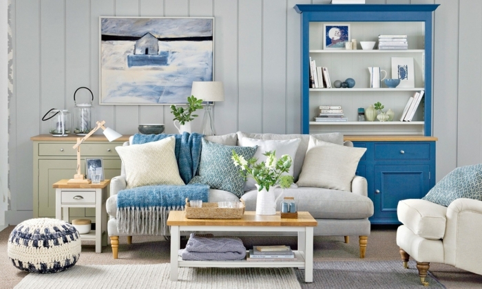 decoracion pisos pequeños, sofa en gris claro con cojines en blanco, azul y amarillo, otomana en el suelo