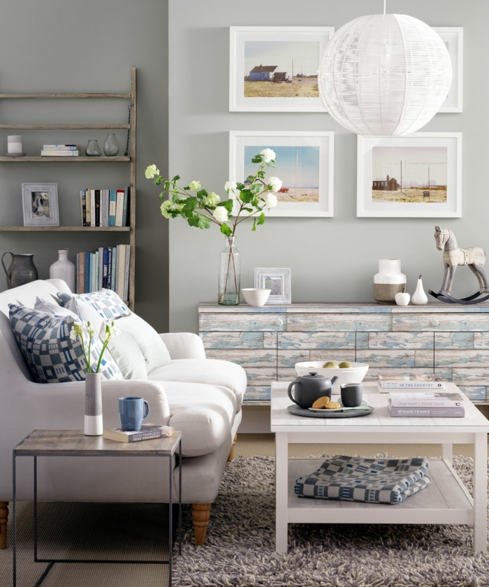 decorar salon pequeño, cuadros en la pared con marcos blancos, lámpara esférica y mesa blanca 