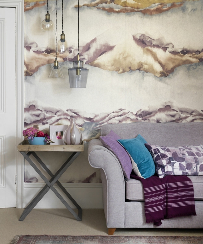 decorar salon pequeño, sofá en gris claro con almohadas de colores y manta en el, lámparas colgantes
