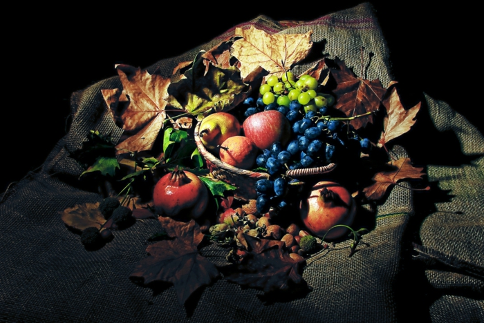 fotos de otoño gratis, en un mantel frutas y hojas de otoño, manzanas, uvas en azul y verde y pomegranate