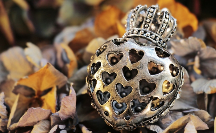 imagenes de otoño, corazon de metal con corona tirada en el suelo entre las hojas arrugadas