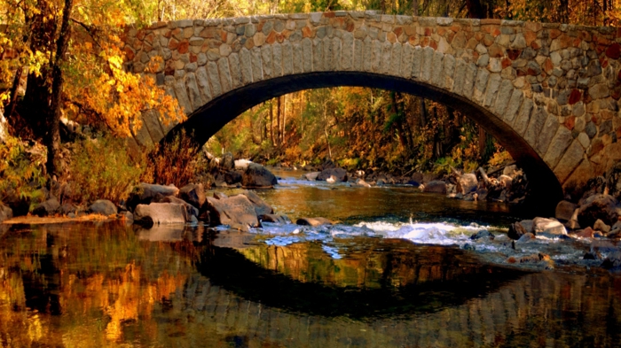 imagenes de otoño, puente de piedras con el agua del rio lleno de piedras y arboles de otoño alrededor
