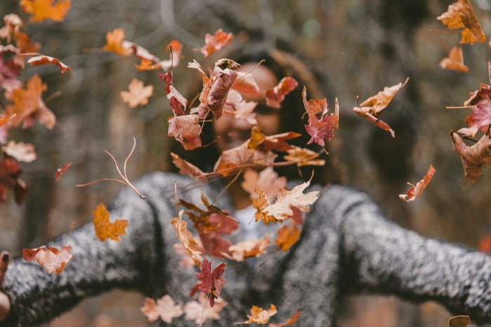 paisajes preciosos, mujer tirando las hojas secas de otoño al aire, feliz de estar de paseo por el bosque