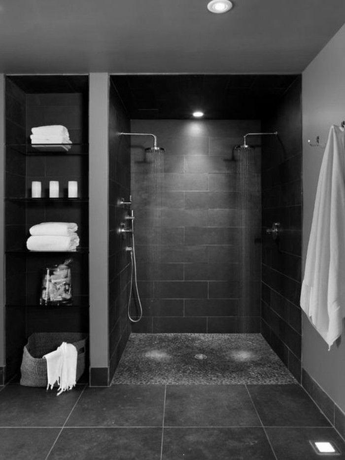 baño decorado en gris oscuro con pequeña cabina de ducha y baldosas grandes, estantería moderna 