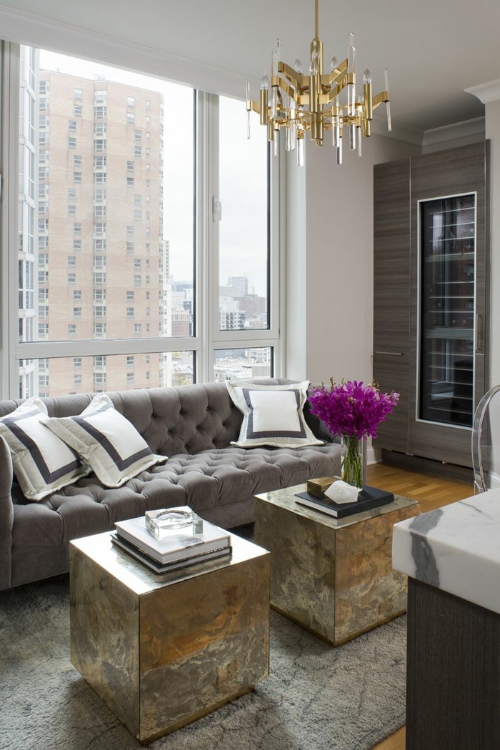 pisos decorados, sofá grande en gris claro con otomanas metálicas con jarrón con flores lilas