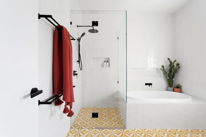suelos ceramicos, suelo de color amarillo con detalles blancos, toalla roja, bañera blanca con azulejos