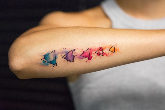 tatuajes geométricos simbolicos con pintura acuarela, tatuaje en el antebrazo con triángulos 