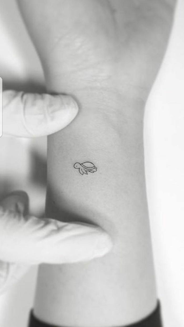 pequeña tortuga tatuada en el antebrazo cerca de la muñeca, ejemplos de tatuajes minimalistas 