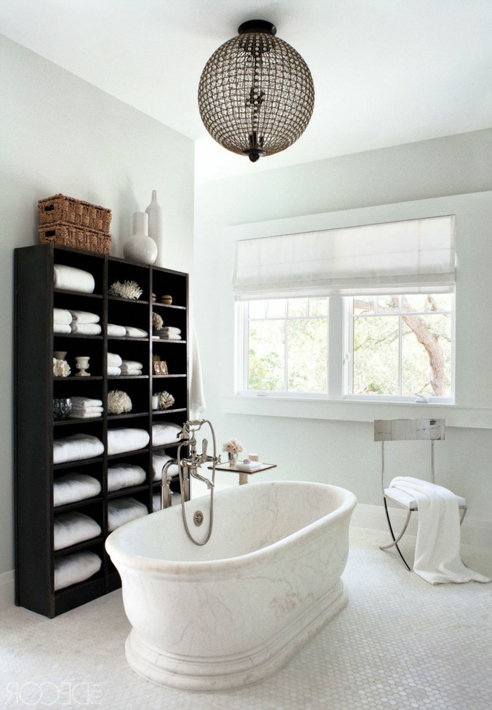 cuarto de baño decorado en colores claros con bañera vintage de mármol, armario de madera