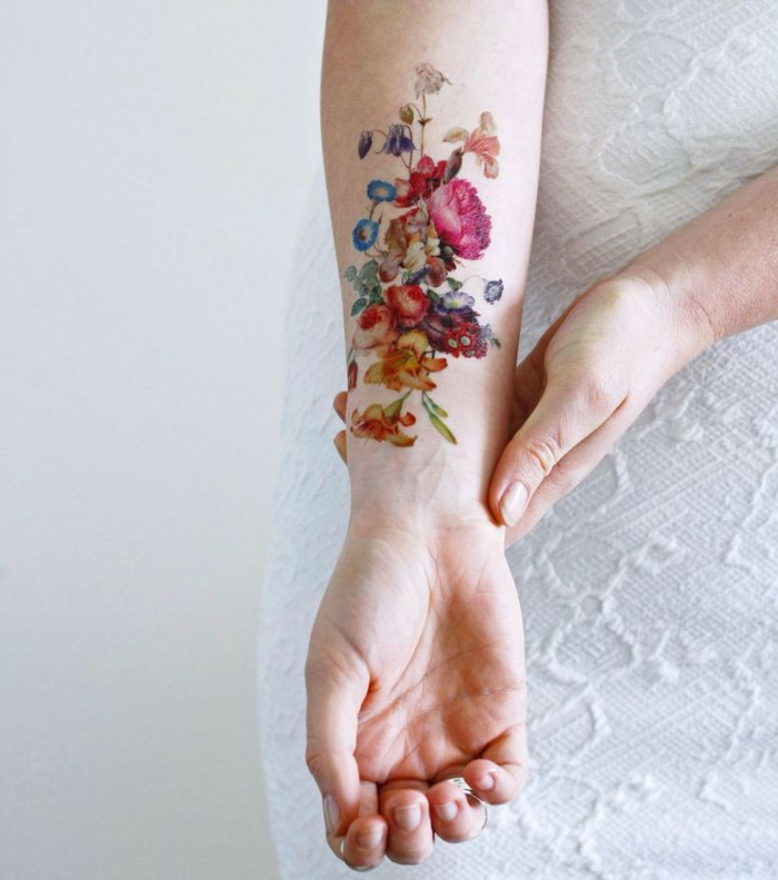 tatuajes tradicionales inspriados en la cultura vintage, antebrazo mujer tatuado con bonitas flores colores intensos
