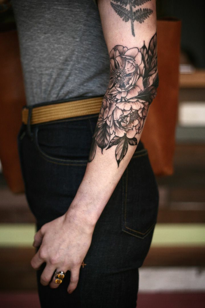 tatuajes en el brazo con motivos vintage, grande tatuaje con elementos florales, peonías tinte negro 