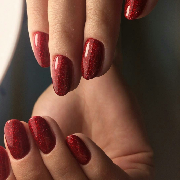 diseños de uñas de acrilico para Navidad, uñas pintadas en color rojo con partículas brillantes, uñas ovaladas 