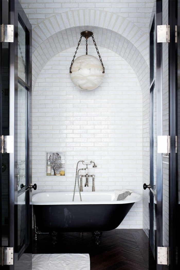 precioso baño decorado en blanco y negro en estilo ecléctico, bañera vintage, suelo de parquet y paredes en blanco 