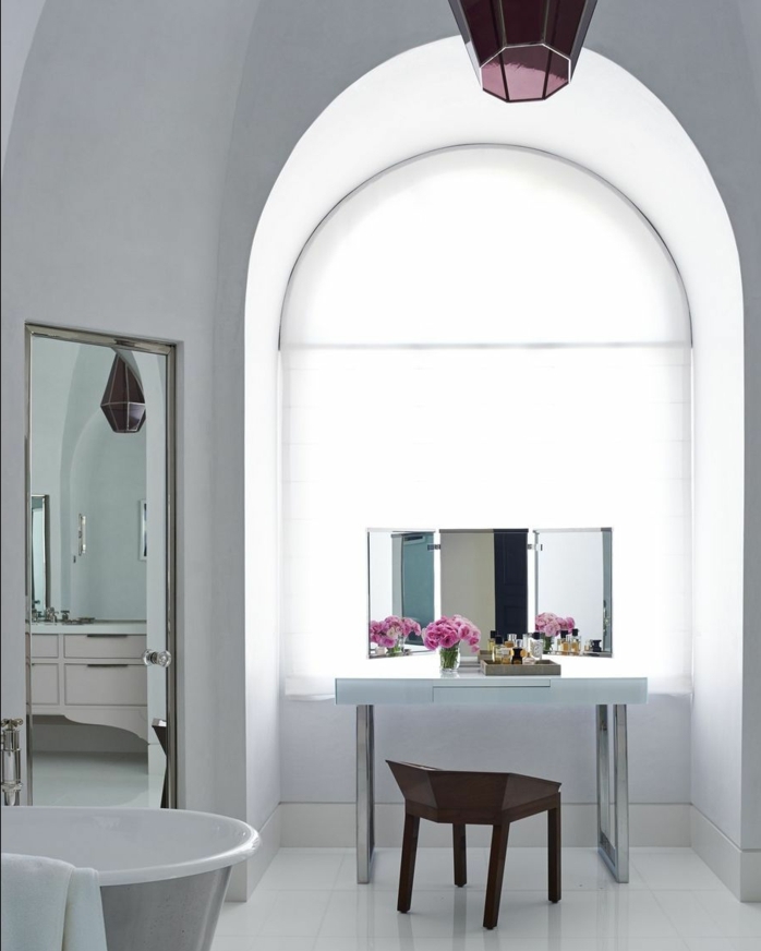 baño decorado en blanco inspirado en la estética vintage con grande espejo y interesante elemento arquitectónico 