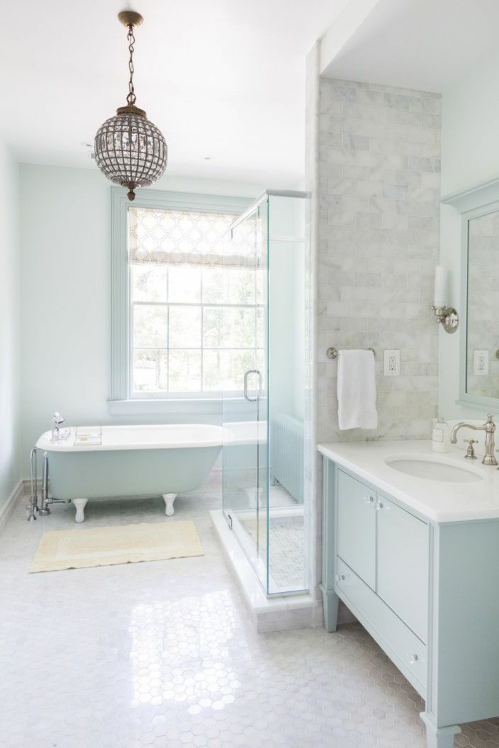 precioso baño decorado en blanco, gris claro y azul bebé, bañera patas garra y lámpara en estilo vintage 