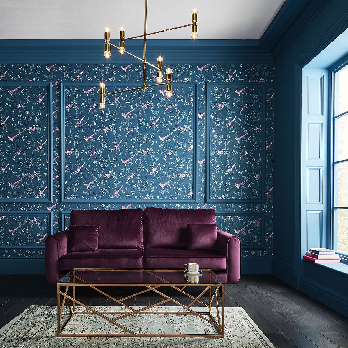 salón de diseño con toque vintage, qué colores se llevan para pintar un salón, sofá de terciopelo en morado, paredes pintadas en azul, papel pintado motivos florales