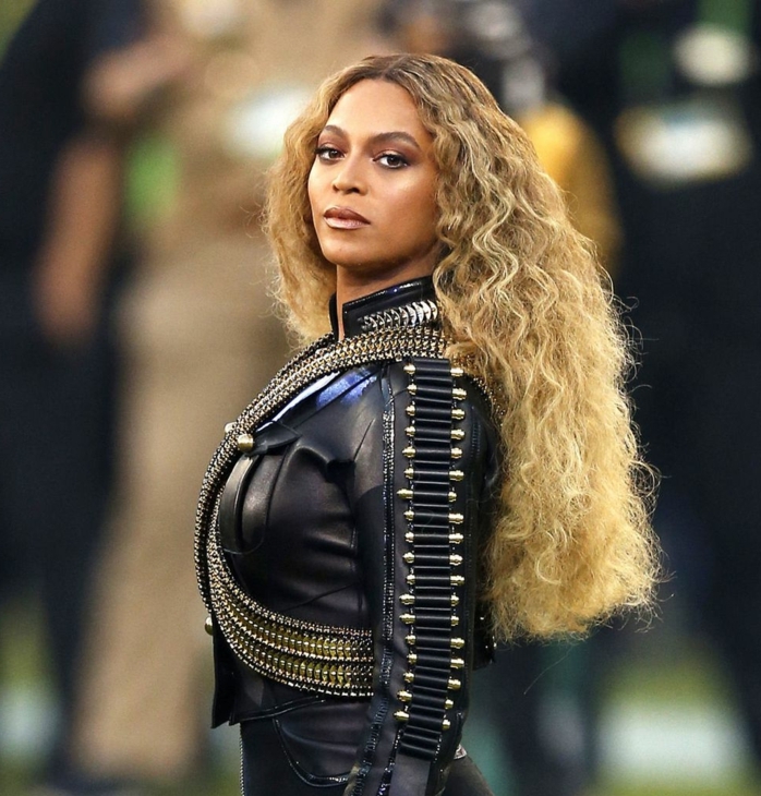 impecable look, Beyonce con melena suelta rizada con mucho volumen, pelo rubio con mechas balayage 