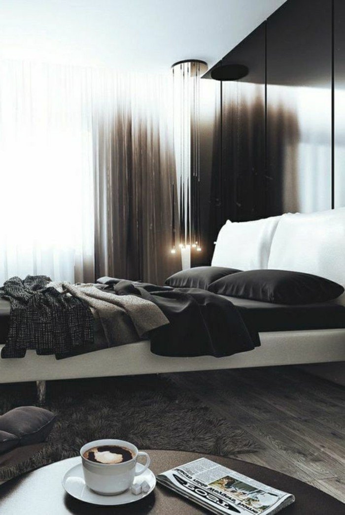 dormitorio gris y blanco de diseño, pared en negro, cama doble en blanco, suelo de madera, mesa oval 